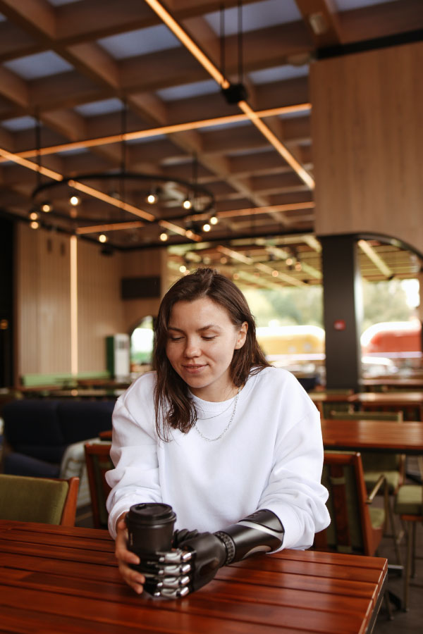 Woman with prosthetic arm having a coffee